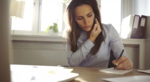 woman on phone and writing on a notepad